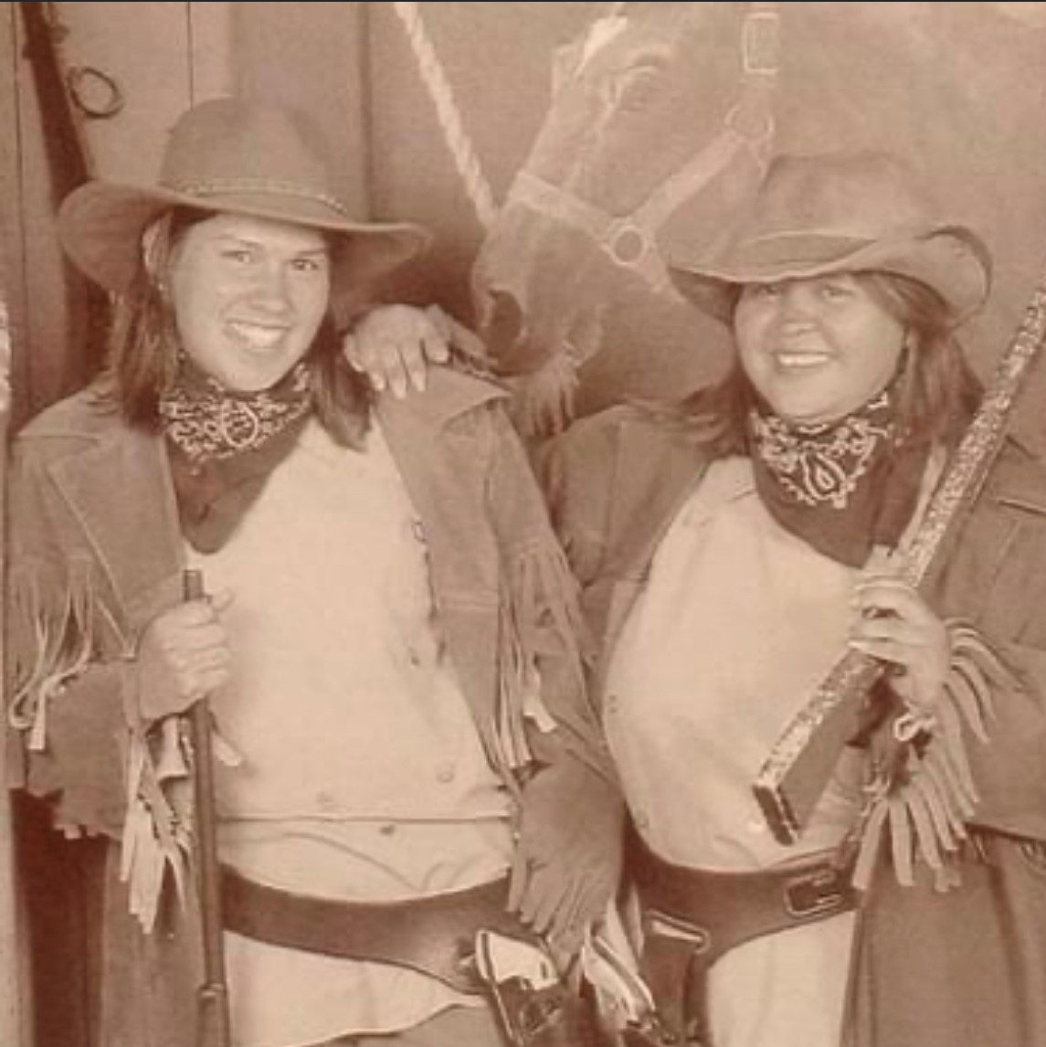 Two women dressed up in Western gear pose for a picture.