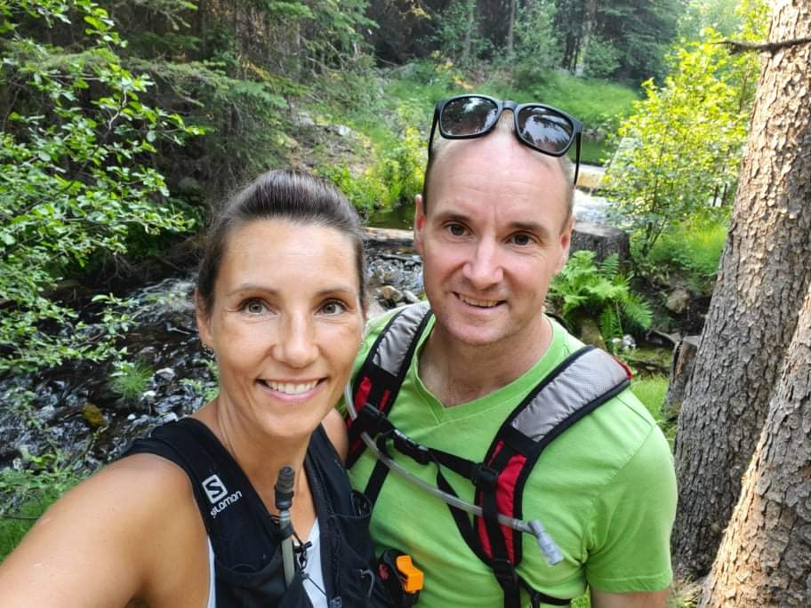 Woman and man hiking in nature with trees.