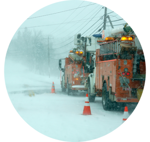 Two utility trucks work to fix downed power lines during a winter storm.