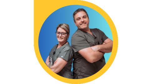 Two people wearing scrubs with their arms crossed stand back to back.