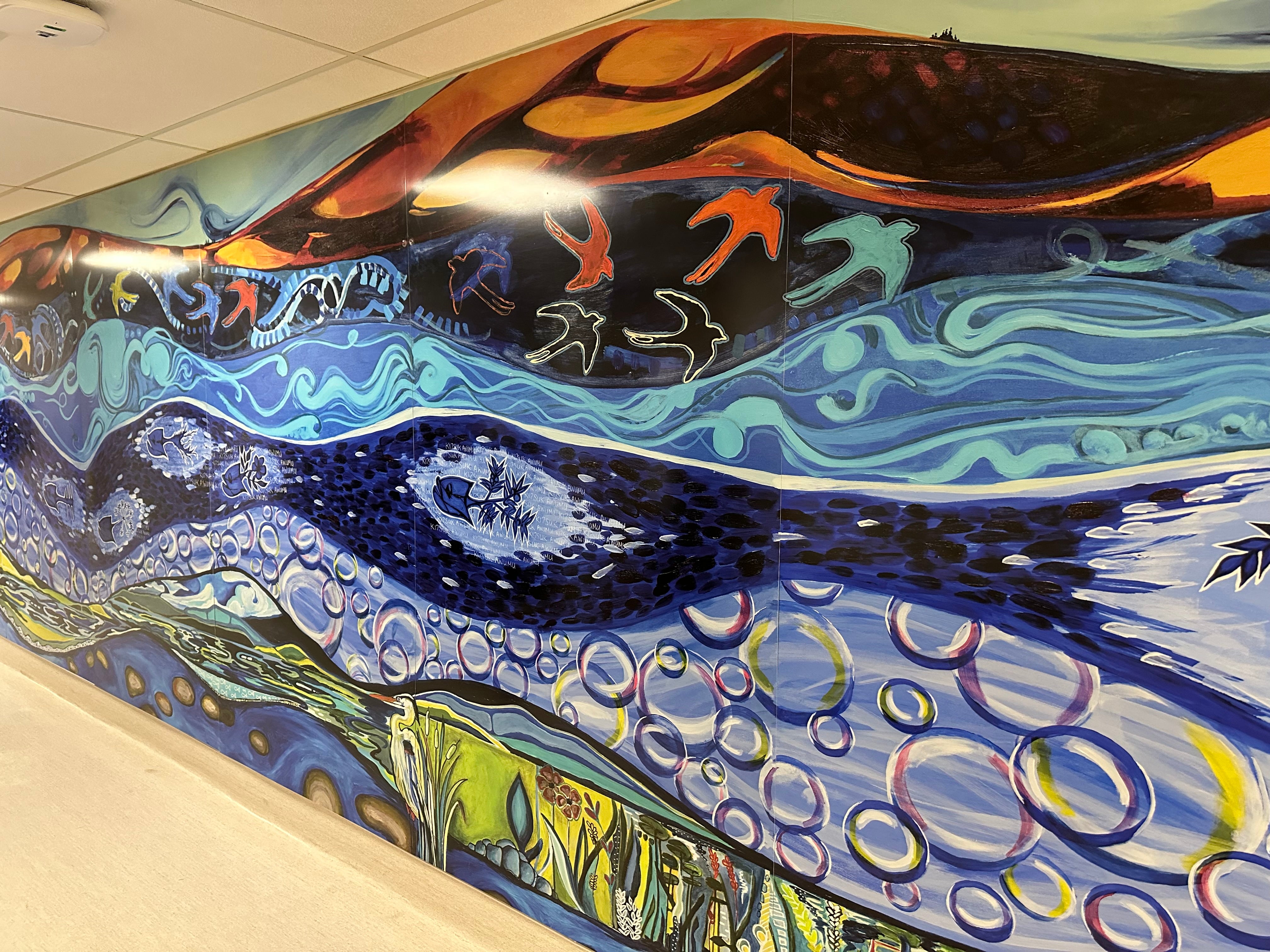 A blue green mural depicting a river and flying birds beneath an orange sky.