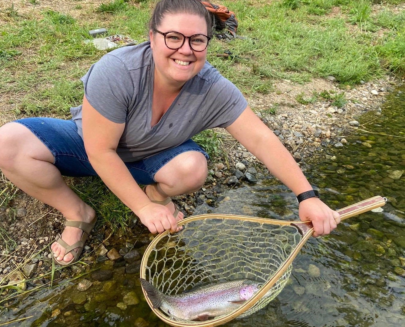 A woman smiles while holding a net with a large fish