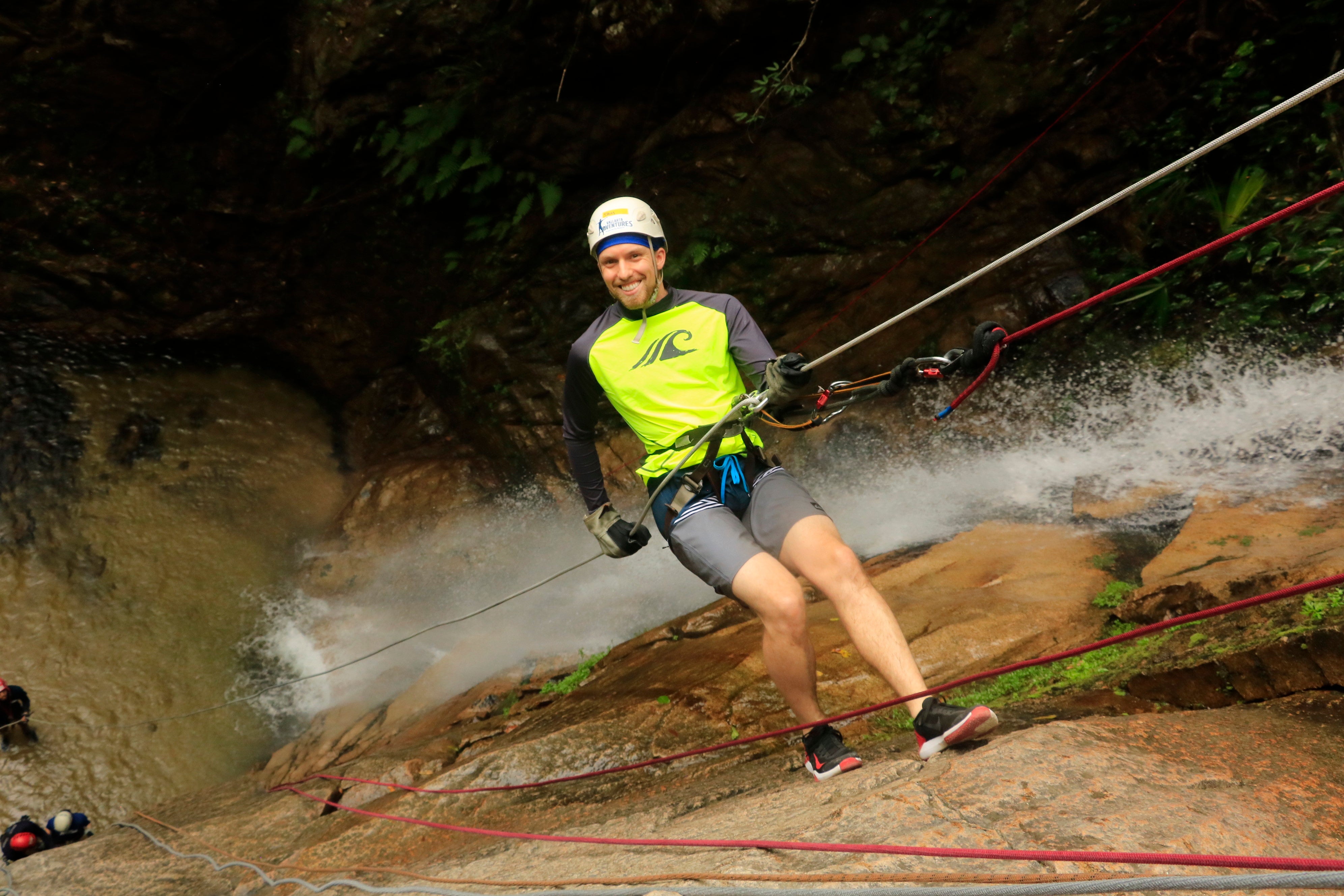 Man hangs off rock face while rock climbing.