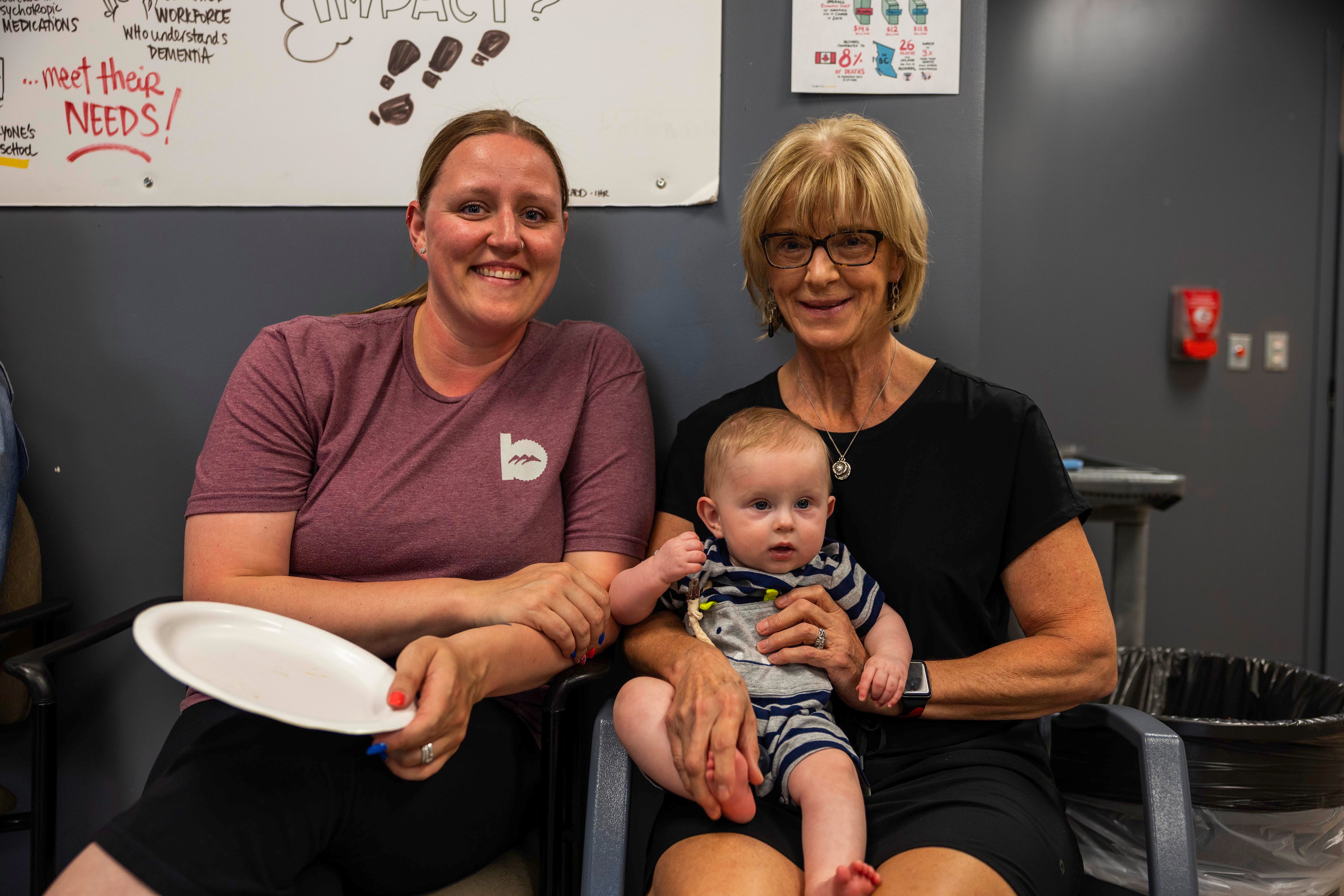 Person holding a baby while sitting next to another person.