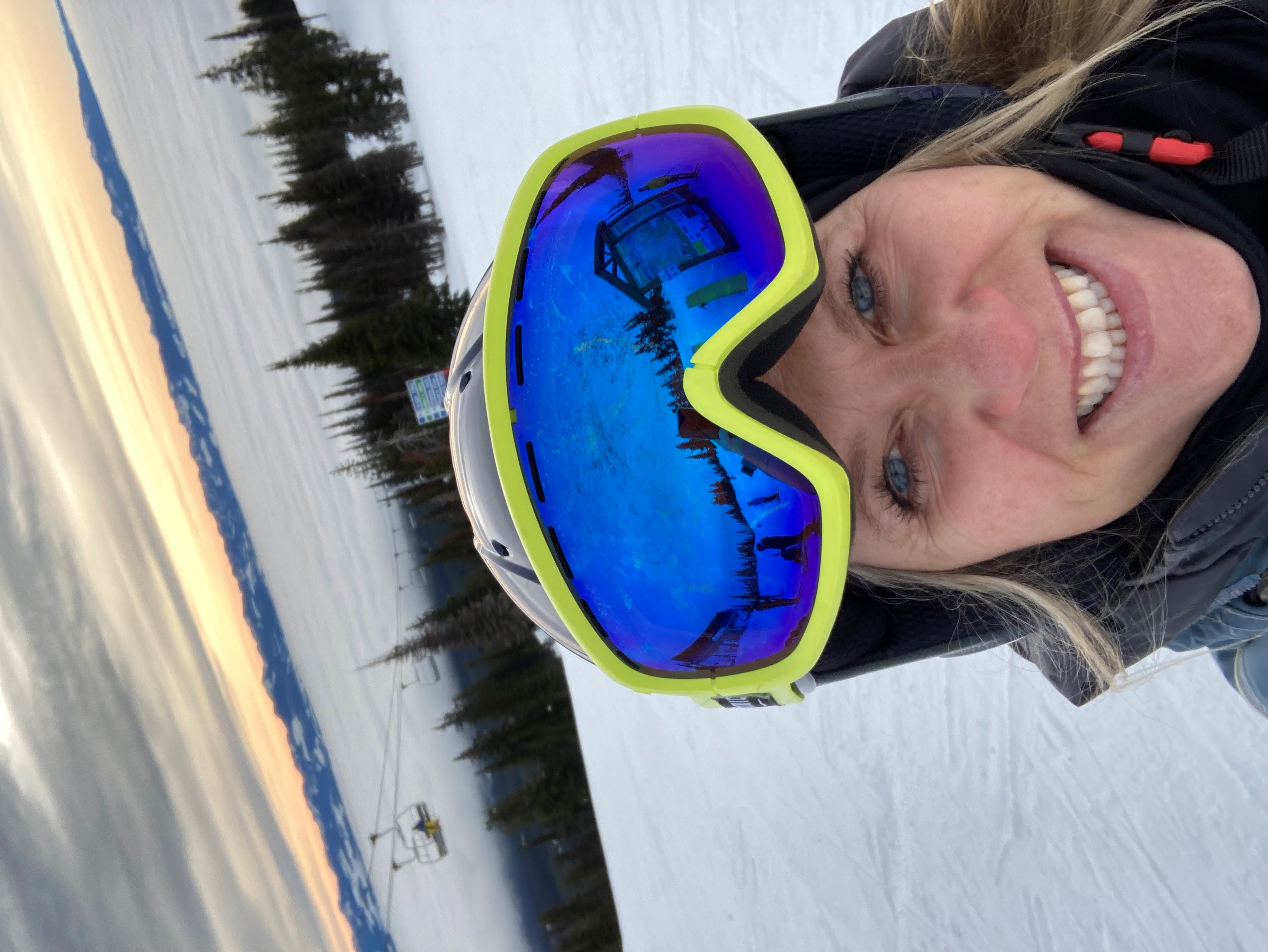 A women taking a selfie on top of a mountain in her ski gear
