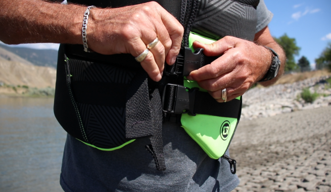Fingers clipping a black and green lifejacket.
