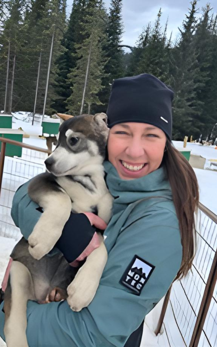 smiling person holding a grey and white dog