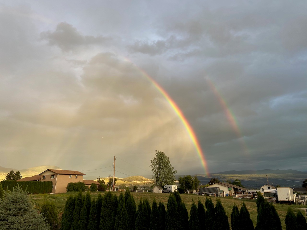 ​​Two rainbows lighting up the sky over houses in a valley