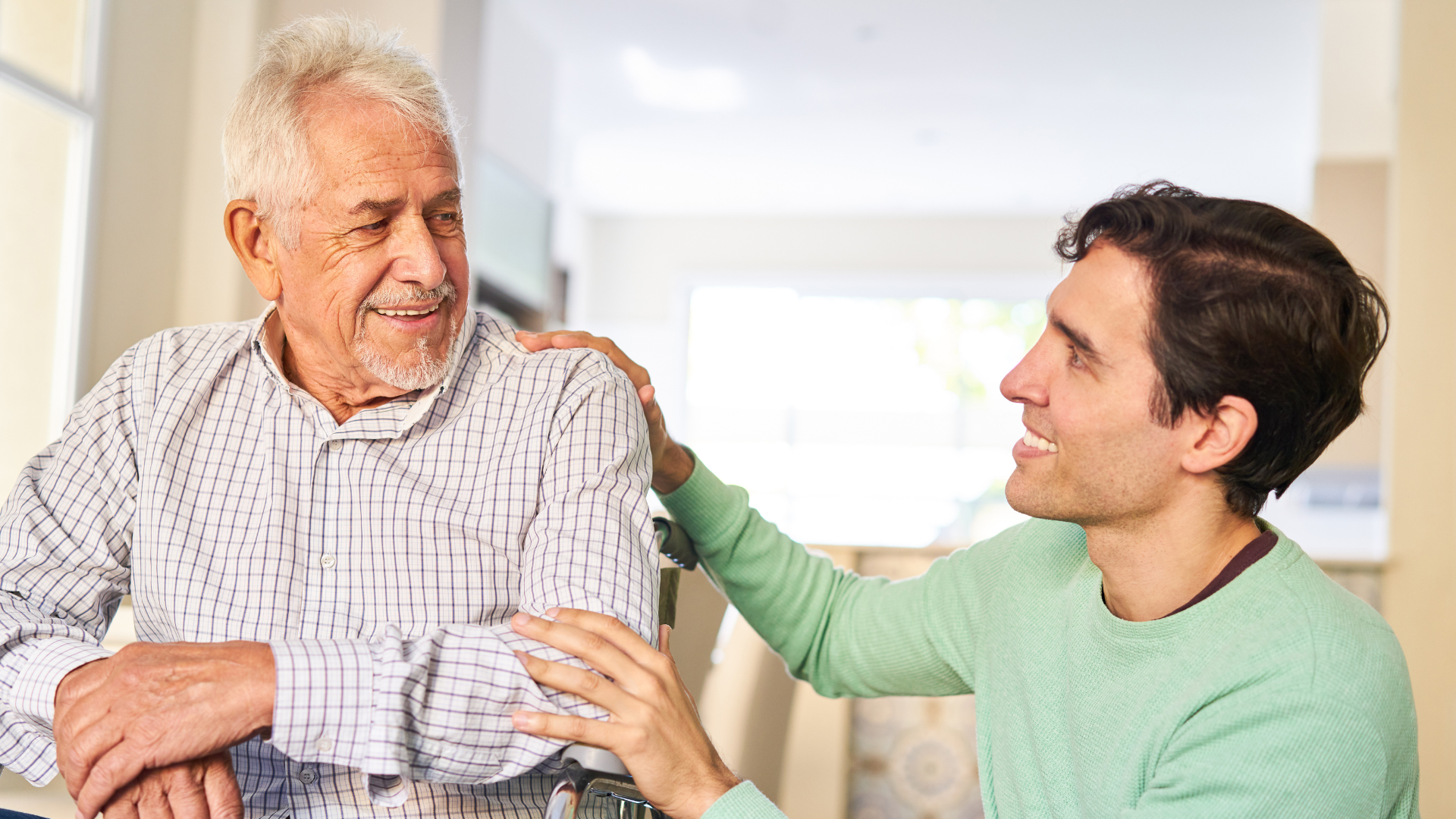An old person in a wheelchair smiling with caregiver.