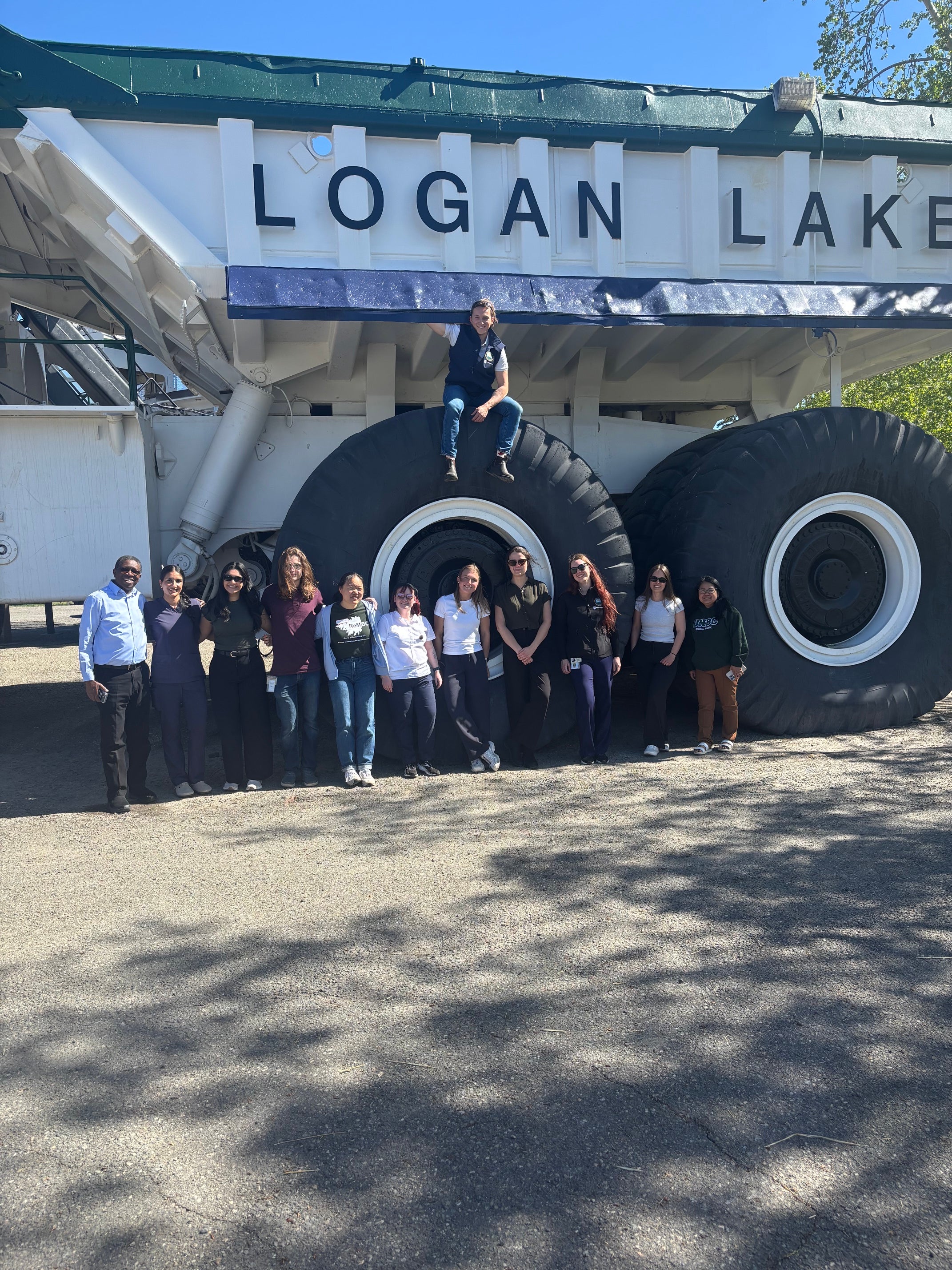 A smiling group of people pose together on a large mining truck