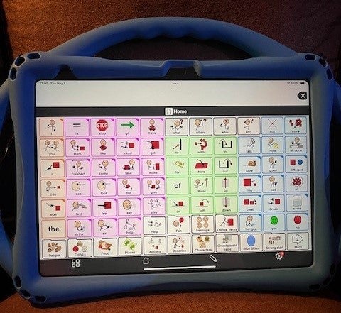 A rectangular electronic device with a blue case and handle. On the screen are stick figures and symbols for words.