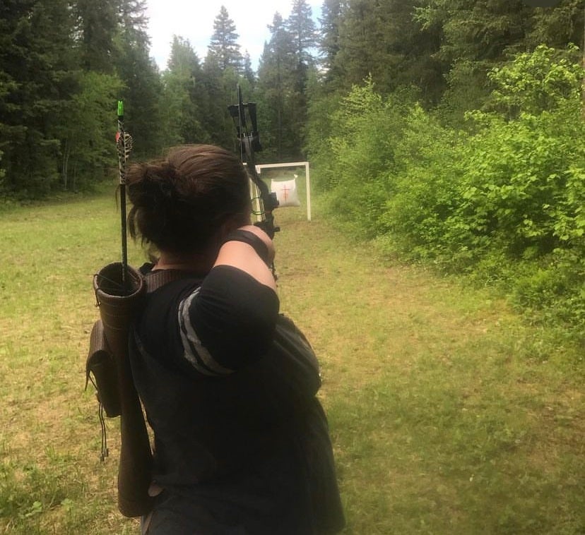 a woman aims a bow and arrow at a target