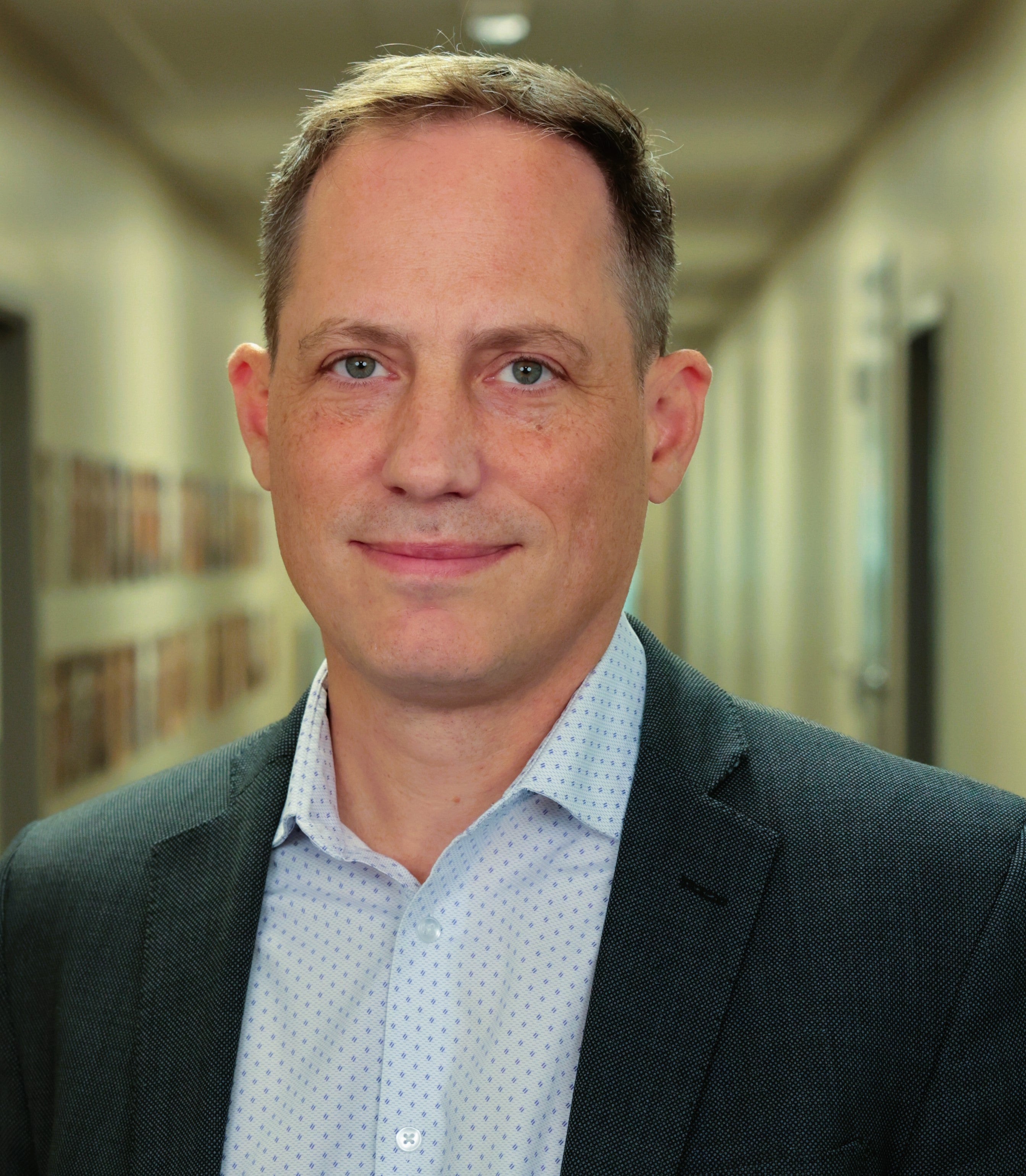 A portrait shot of a man wearing a business suit and undershirt.