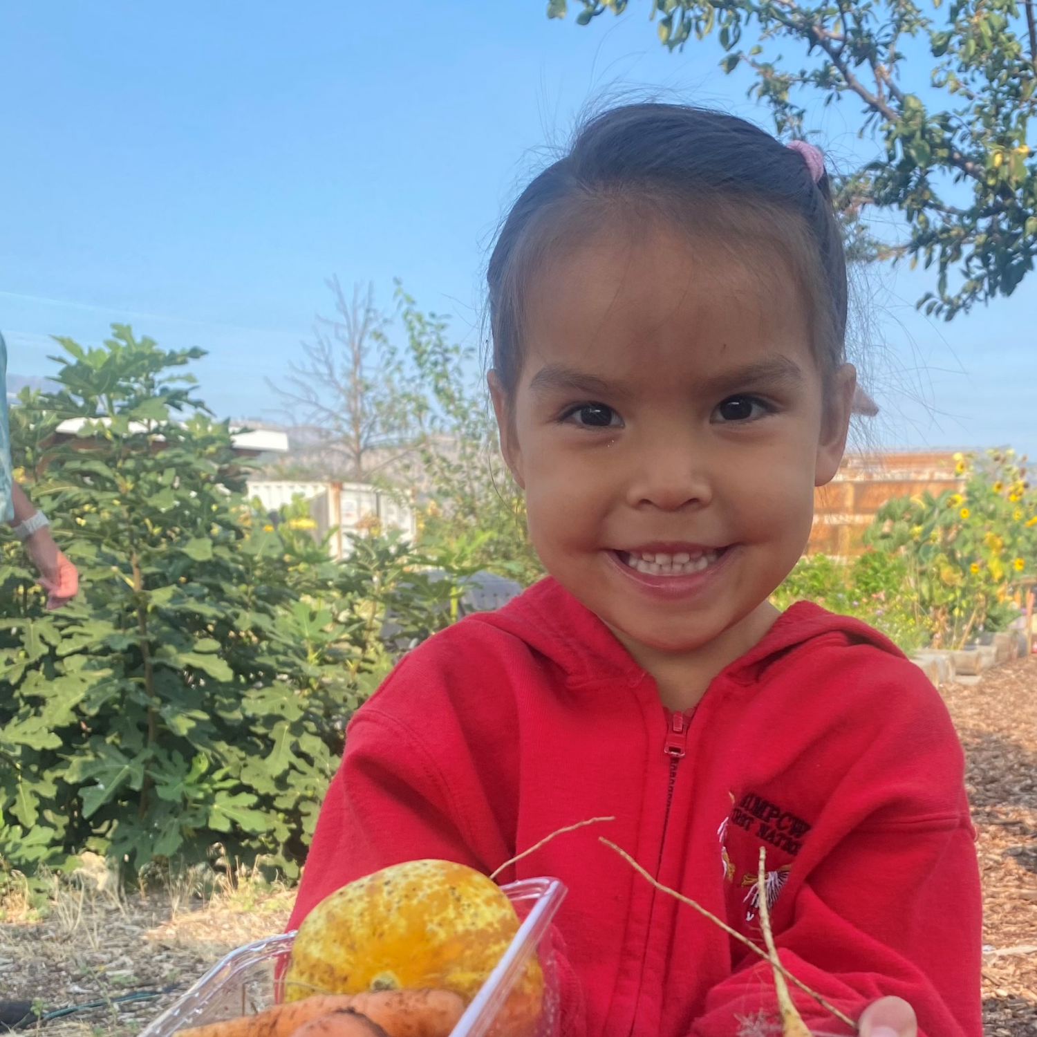 a young person smiling in a red sweater while holding food