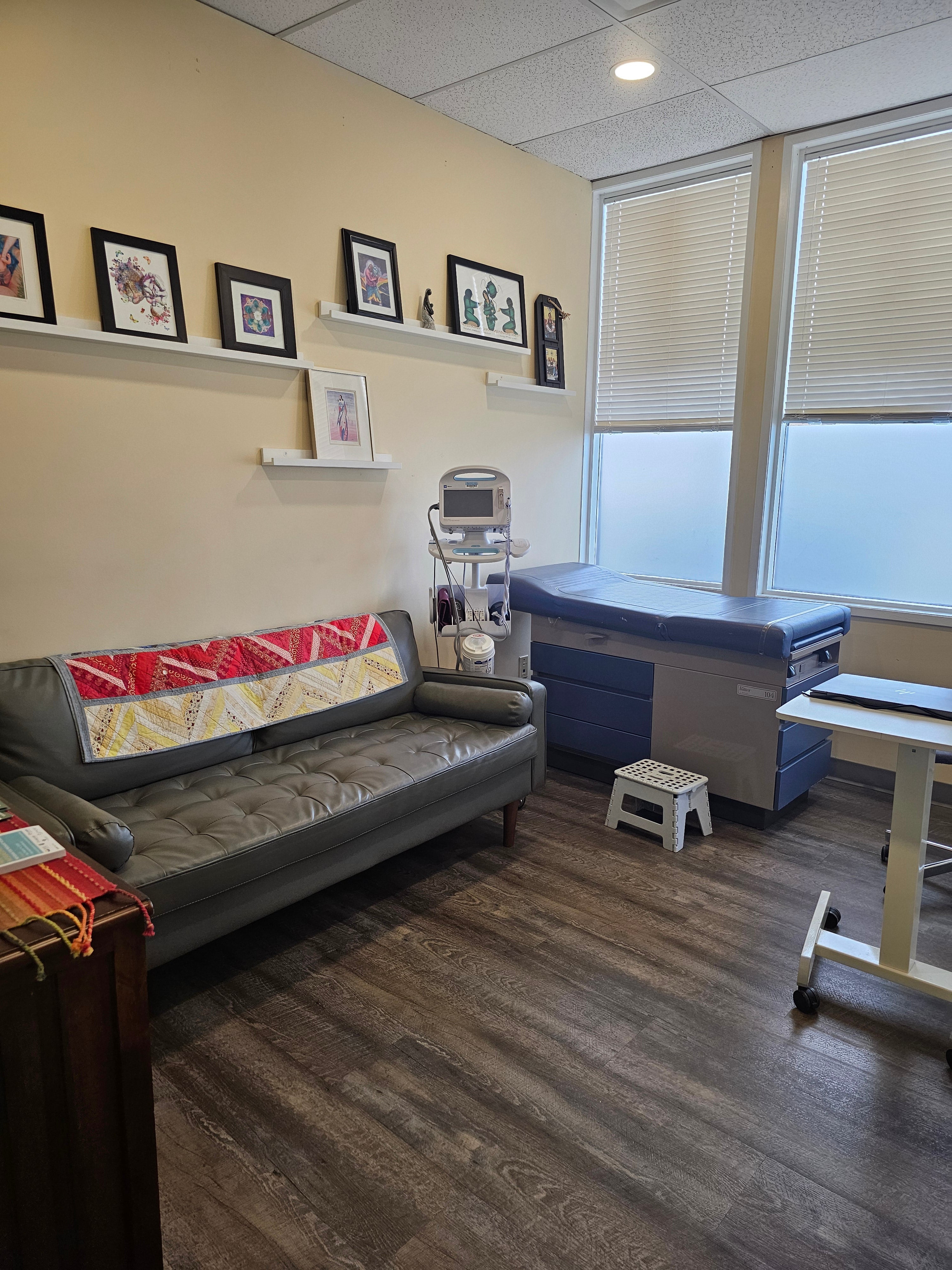 An examination room featuring a couch, exam bed and medical equipment.