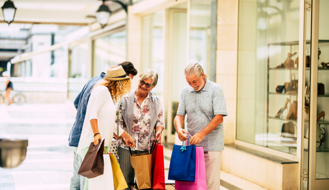 Four people with shopping bags in a mall.