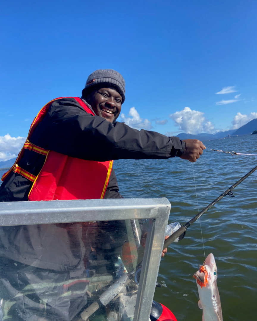 Person fishing from a boat and catching a fish on a sunny day.