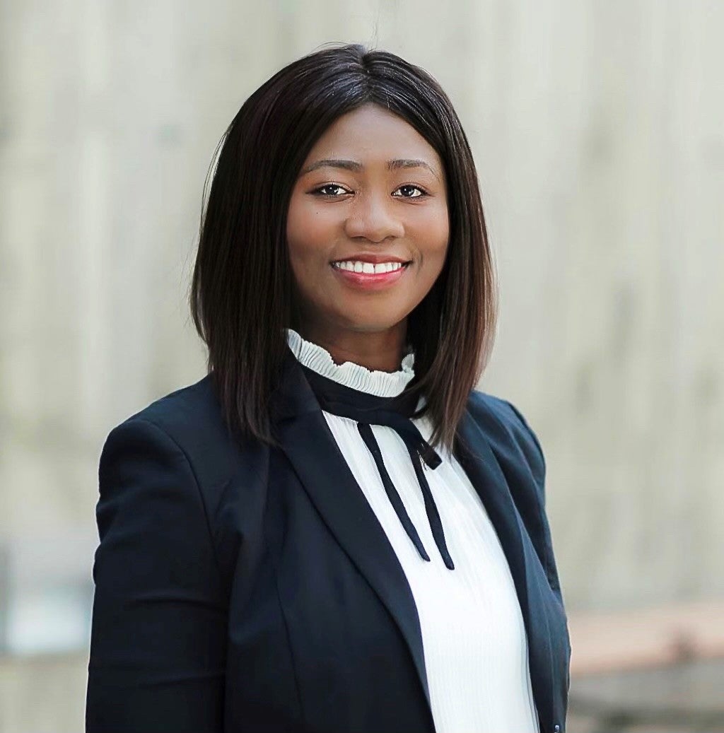 A smiling woman wearing lawyer attire poses for a picture.