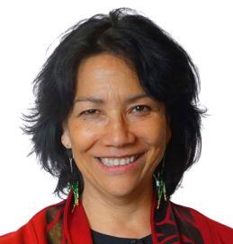 A headshot of a smiling person with short dark hair.