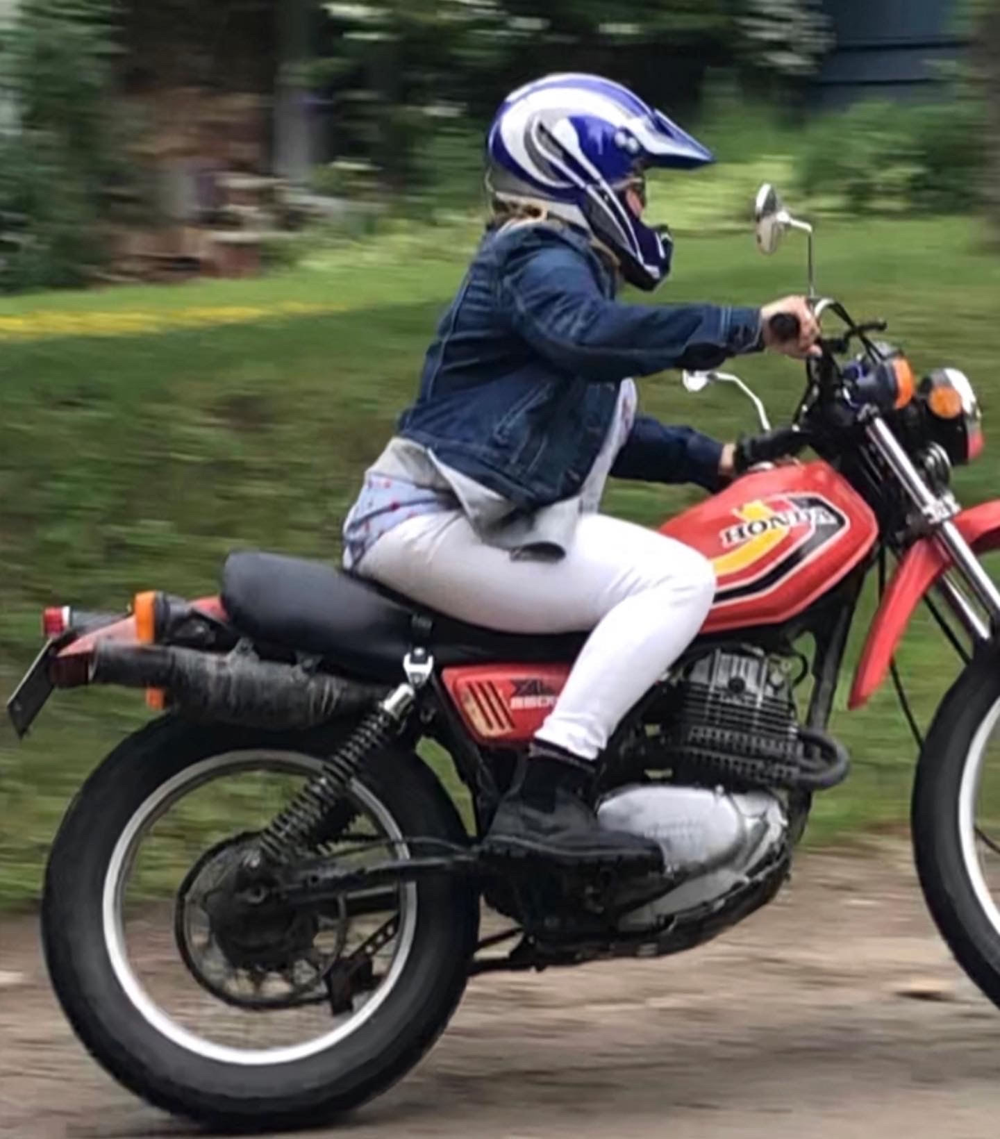 A woman rides a red motorcycle. 
