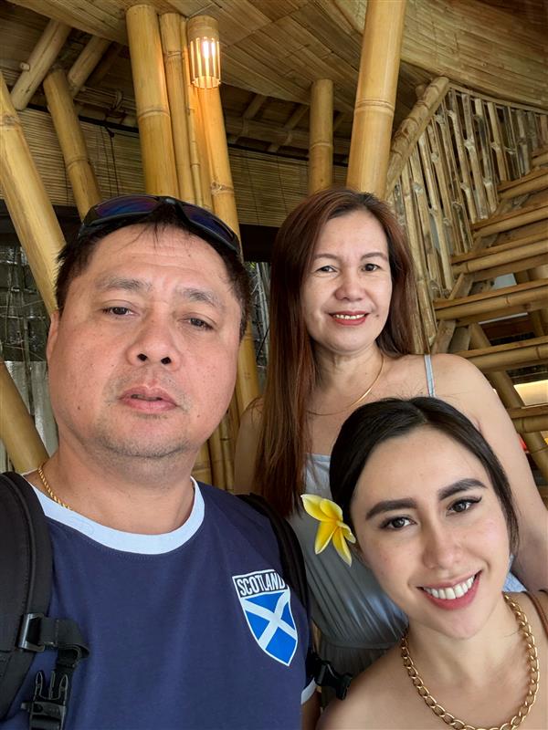 Three people pose for a selfie taken inside a home built from bamboo.