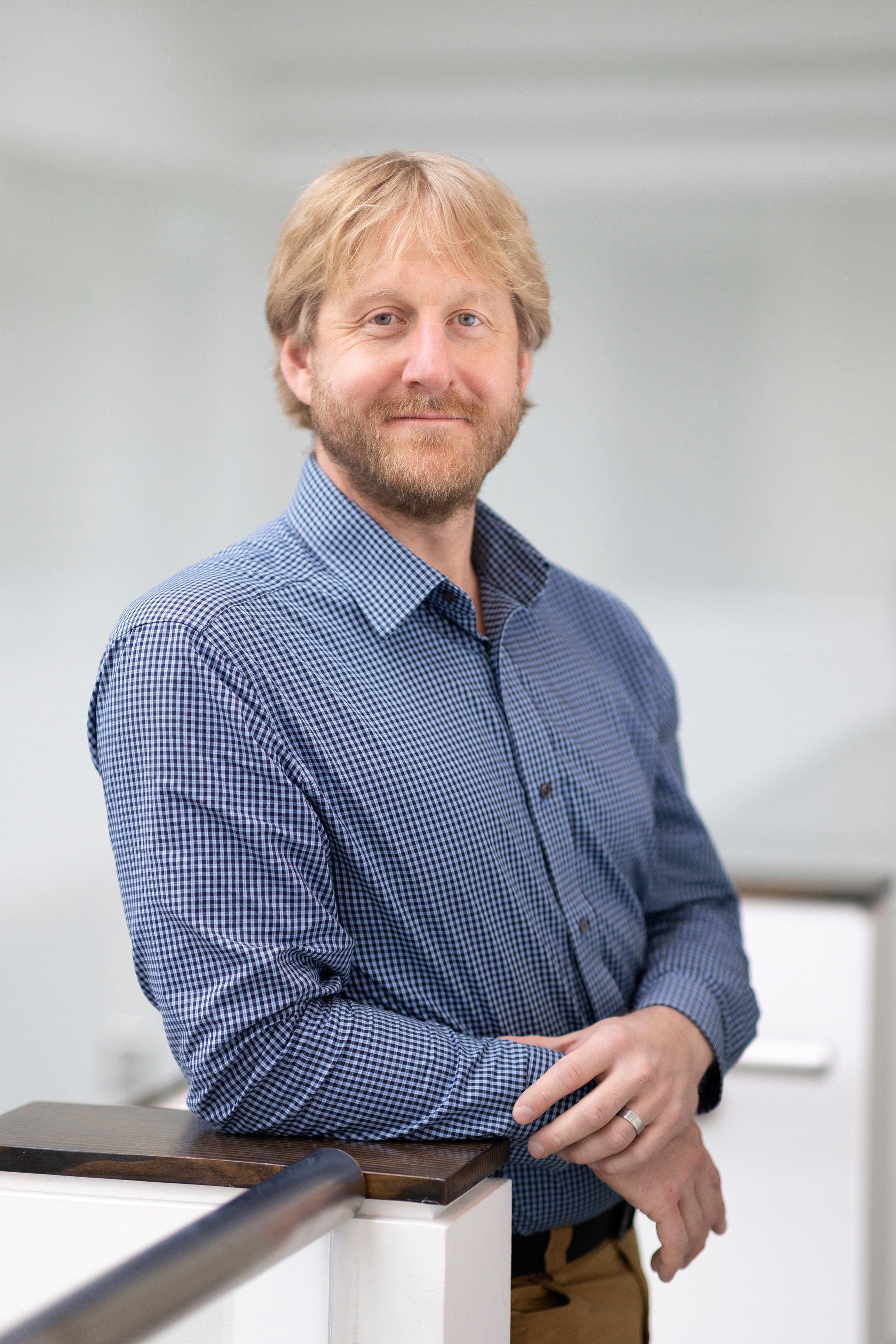 Profile shot of a smiling person with blonde hair and a full beard wearing a blue button up shirt.