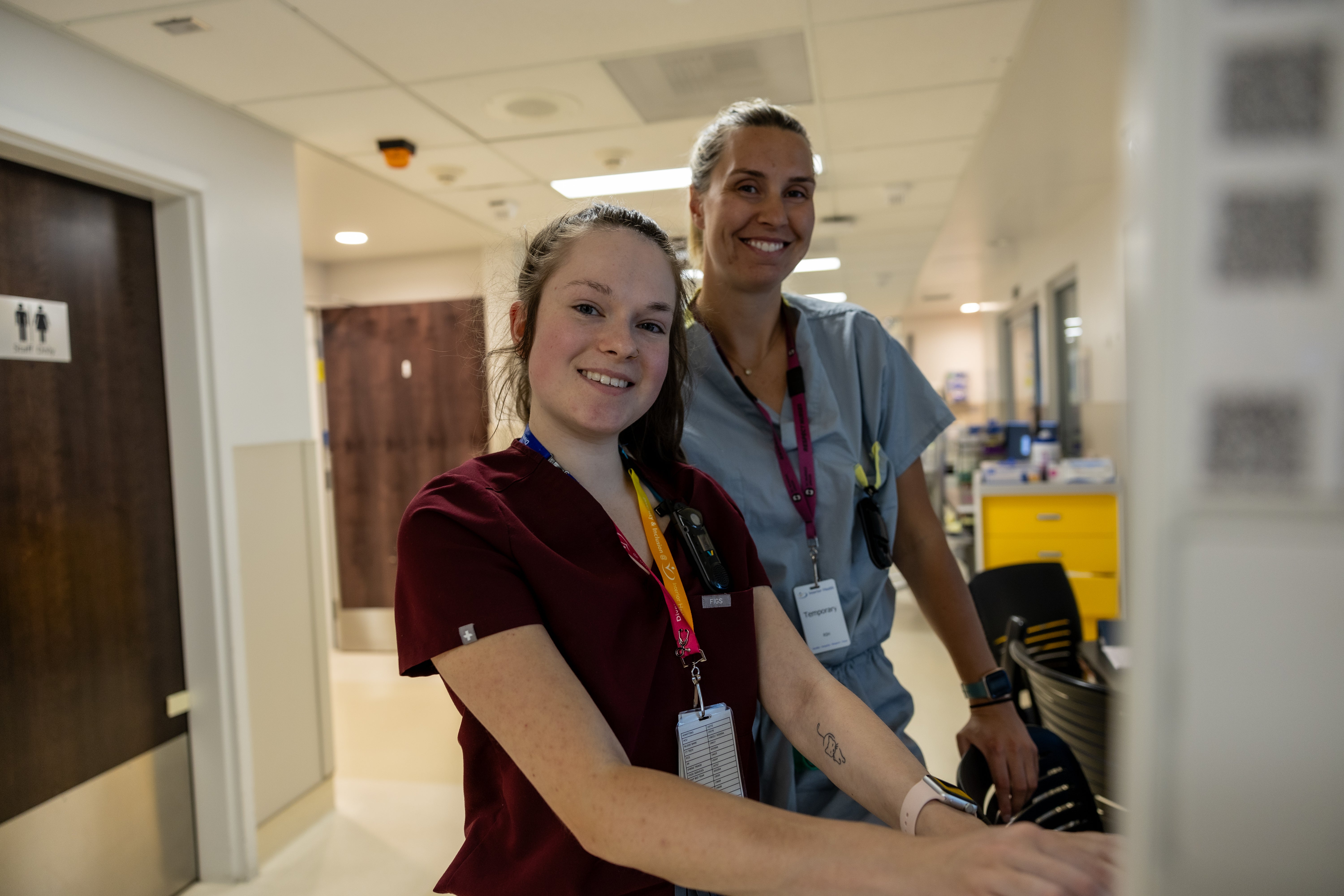 Two health-care professionals pose for a photo in a hospital corridor.