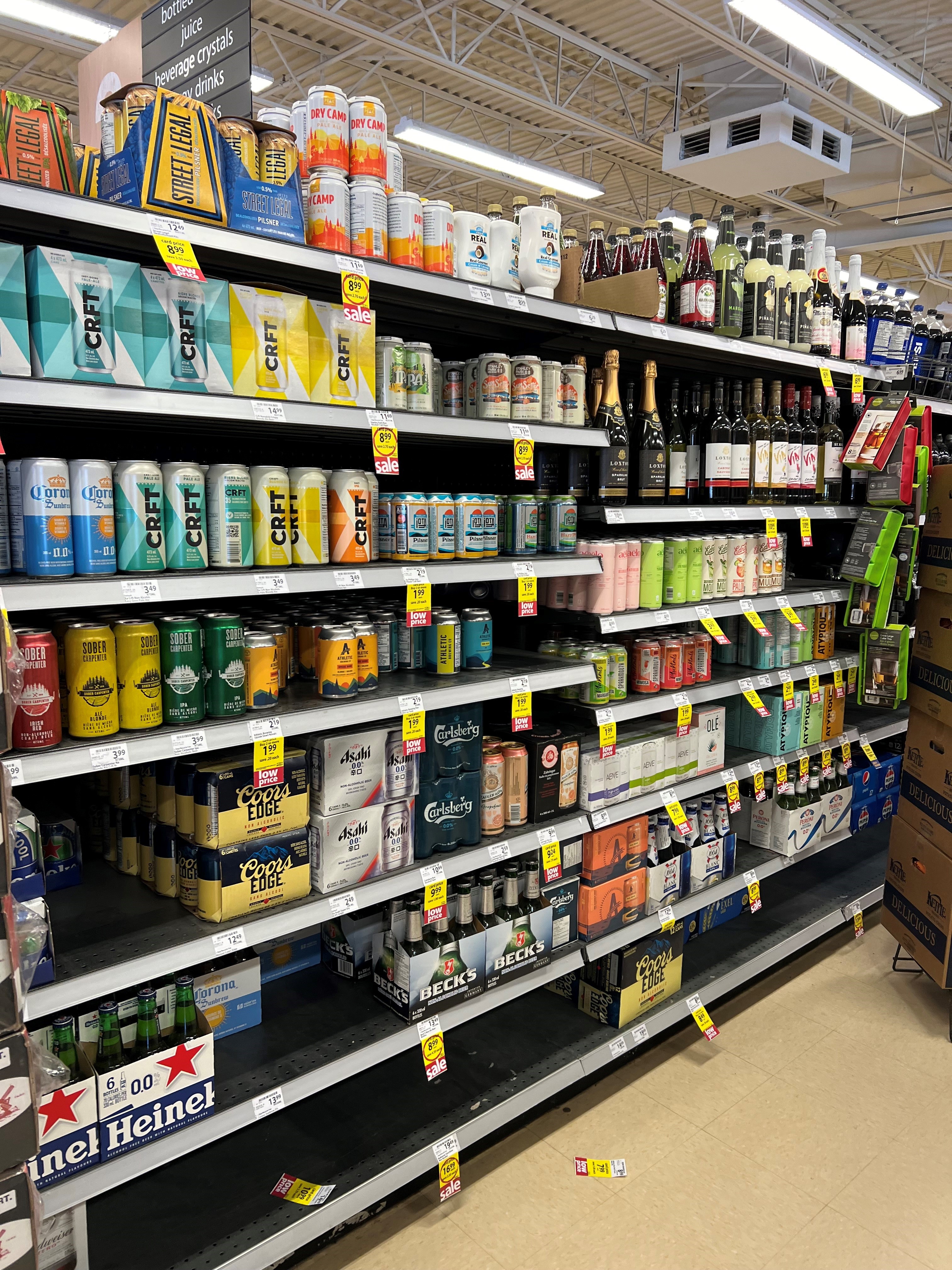 A shelf of beverages in cans and bottles at a grocery store
