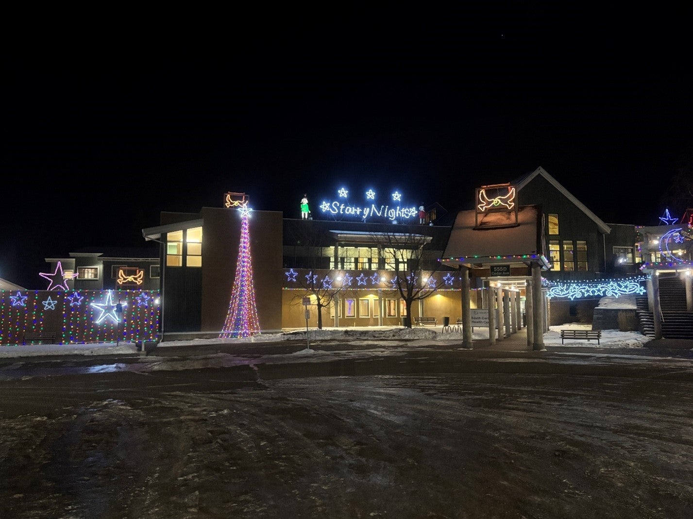 A two-storey building is lit up with Christmas lights. There are stars, a tree and a sign that says Starry Nights. It's dark outside and there's snow on the ground.