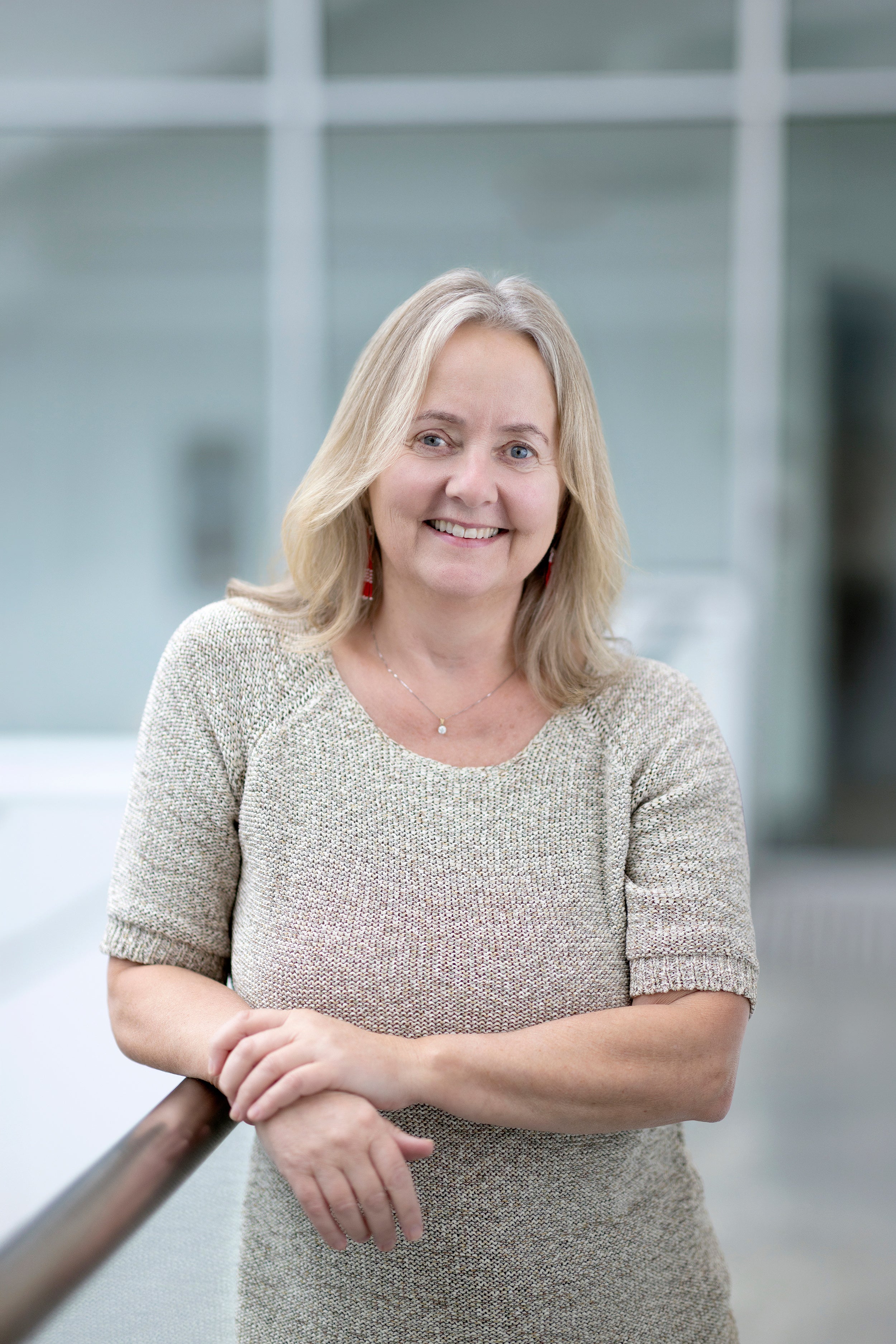 Profile shot of a smiling person with long blonde hair wearing a light-coloured shirt.