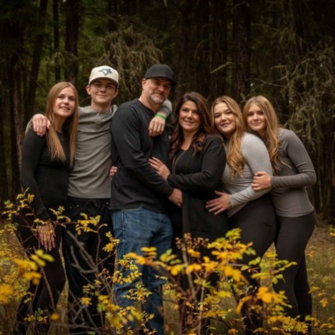 a family taking a picture together outdoors in the autumn. 