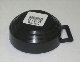 A black round disk with a small handle labelled Radon under a barcode and serial number