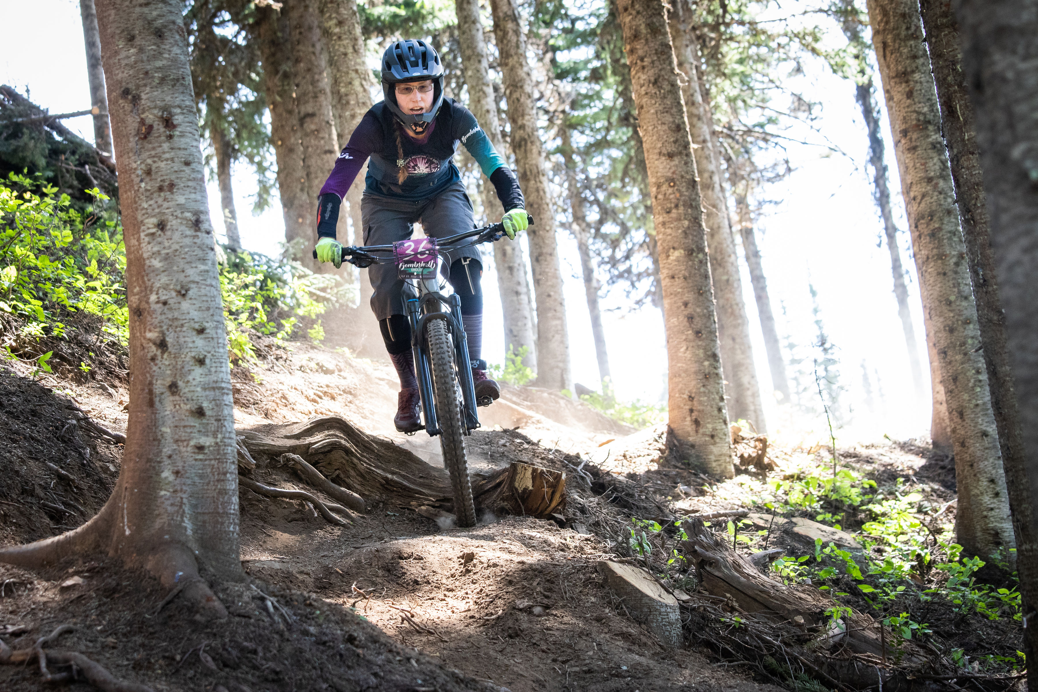 Woman cycling on rugged path through tree forest
