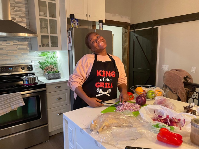 A woman cooking in the kitchen, wearing an apron that reads King of the Grill.