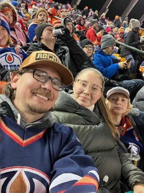 Man, woman, and boy sitting in a crowd at sporting event