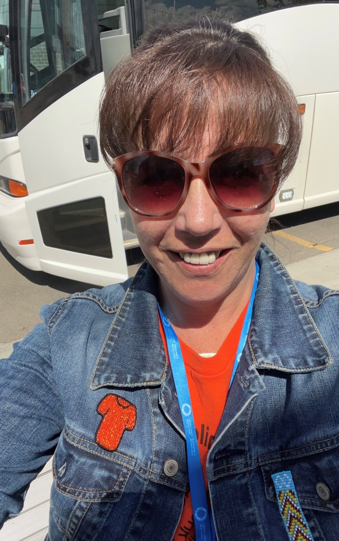 Woman wearing sunglasses, jean jacket and t-shirt.