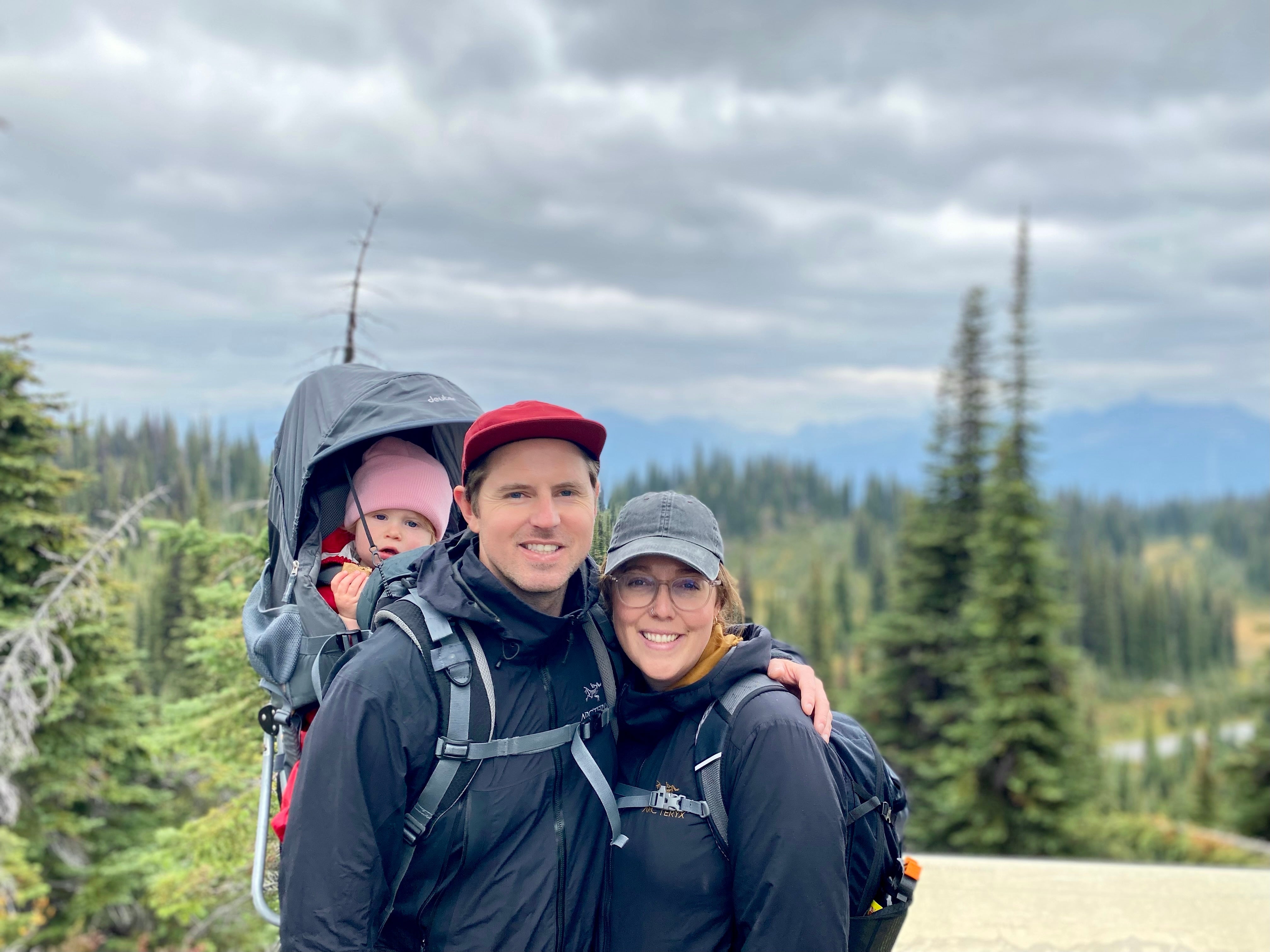 A couple out on a hike with their child in the forest.