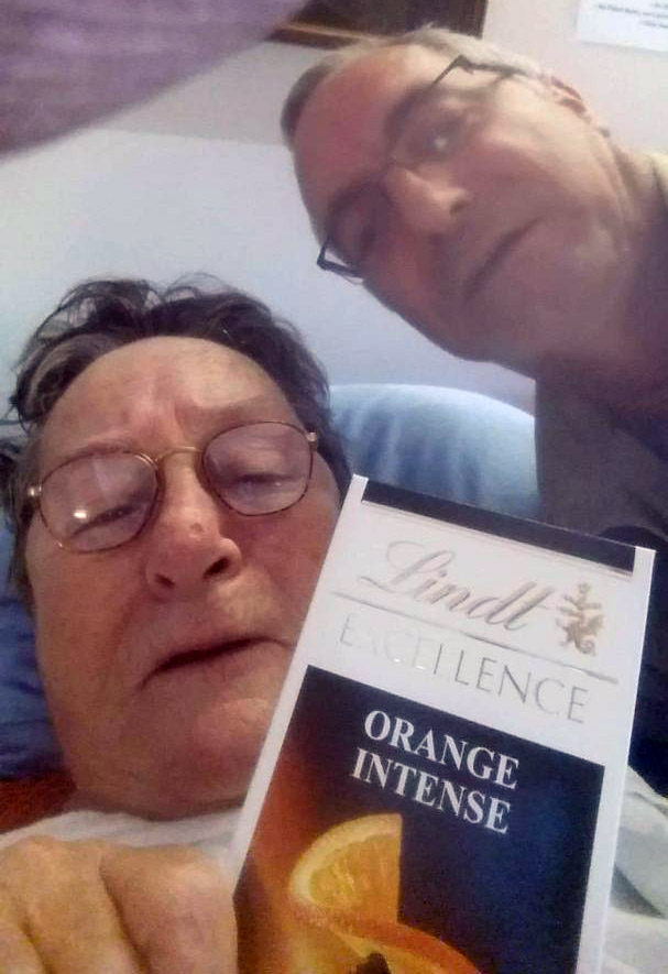 A selfie of two people, with a Lindt Orange Intense chocolate bar in the foreground.