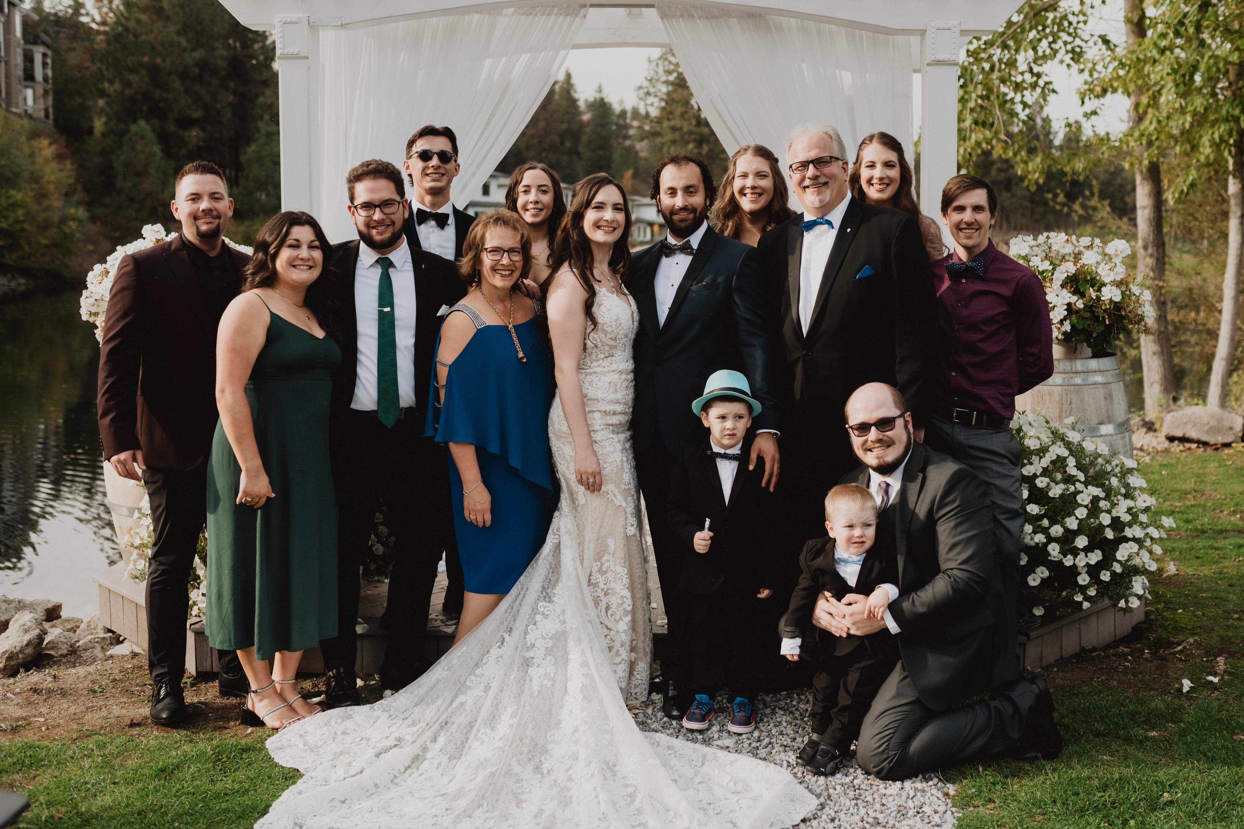 An outdoor group photo at a wedding with the newlyweds in the middle.