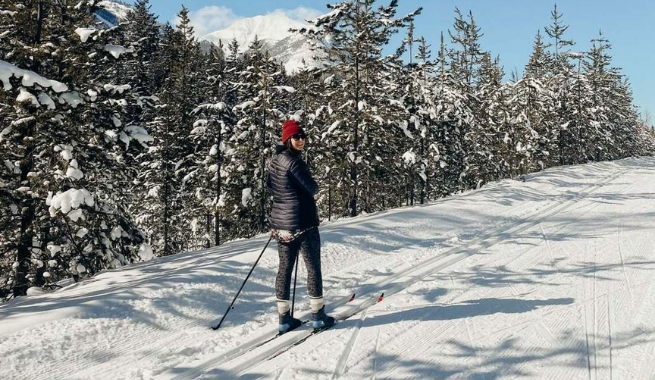 A woman on cross-country skis posing for a picture on a winter trail.