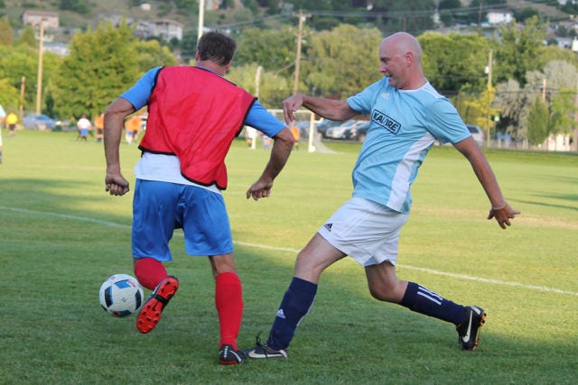 Two players compete for the ball on a soccer pitch.