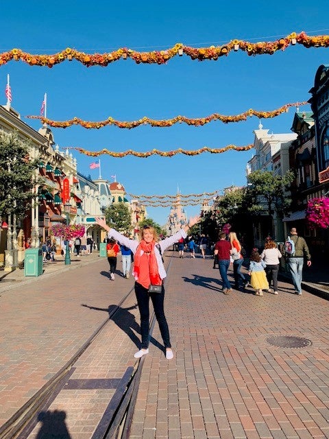 A woman standing on a brick road with orange streamers stretched across the street at intervals.