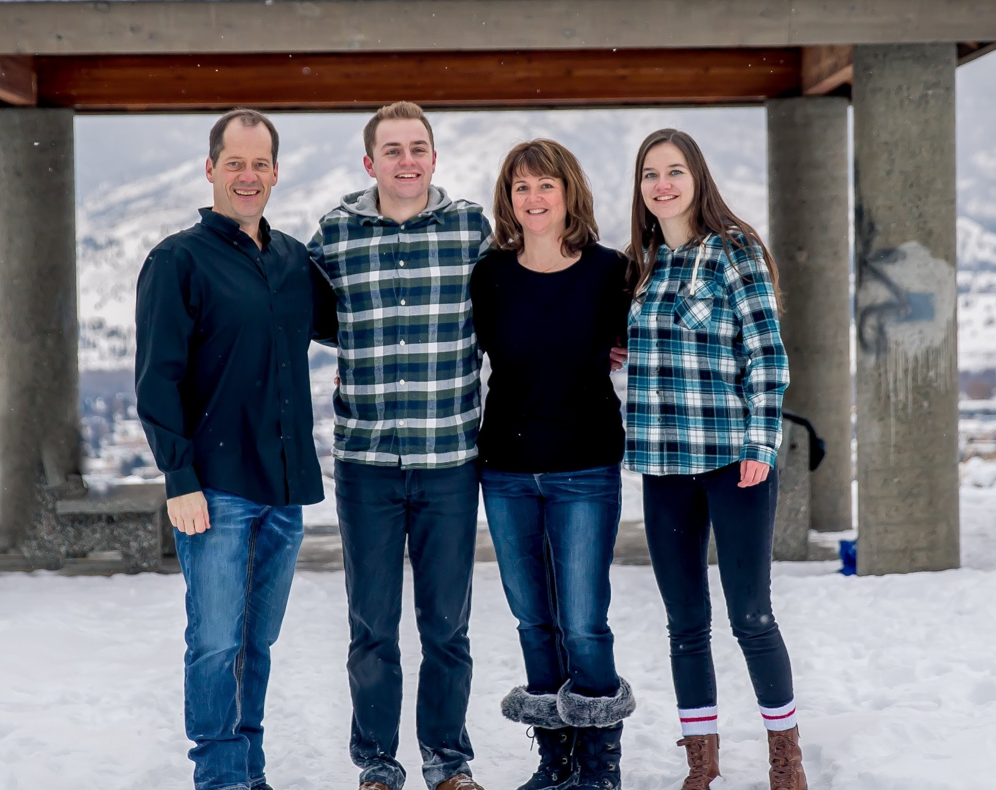 Four people pose for a picture outside in the snow.