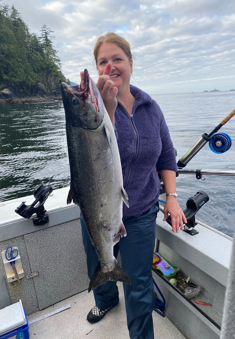 A person in a boat on the water displays the fish they caught.