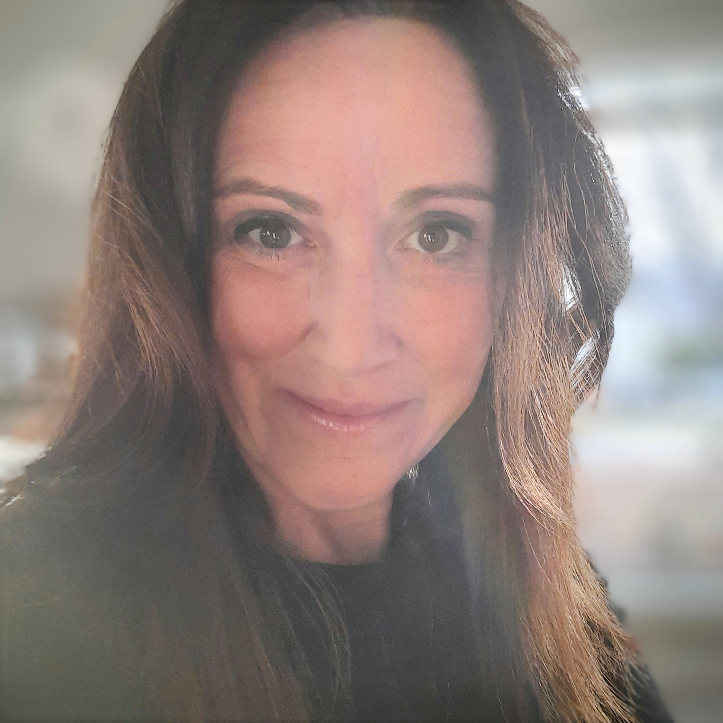 Woman with long dark hair and dark top smiling at camera.