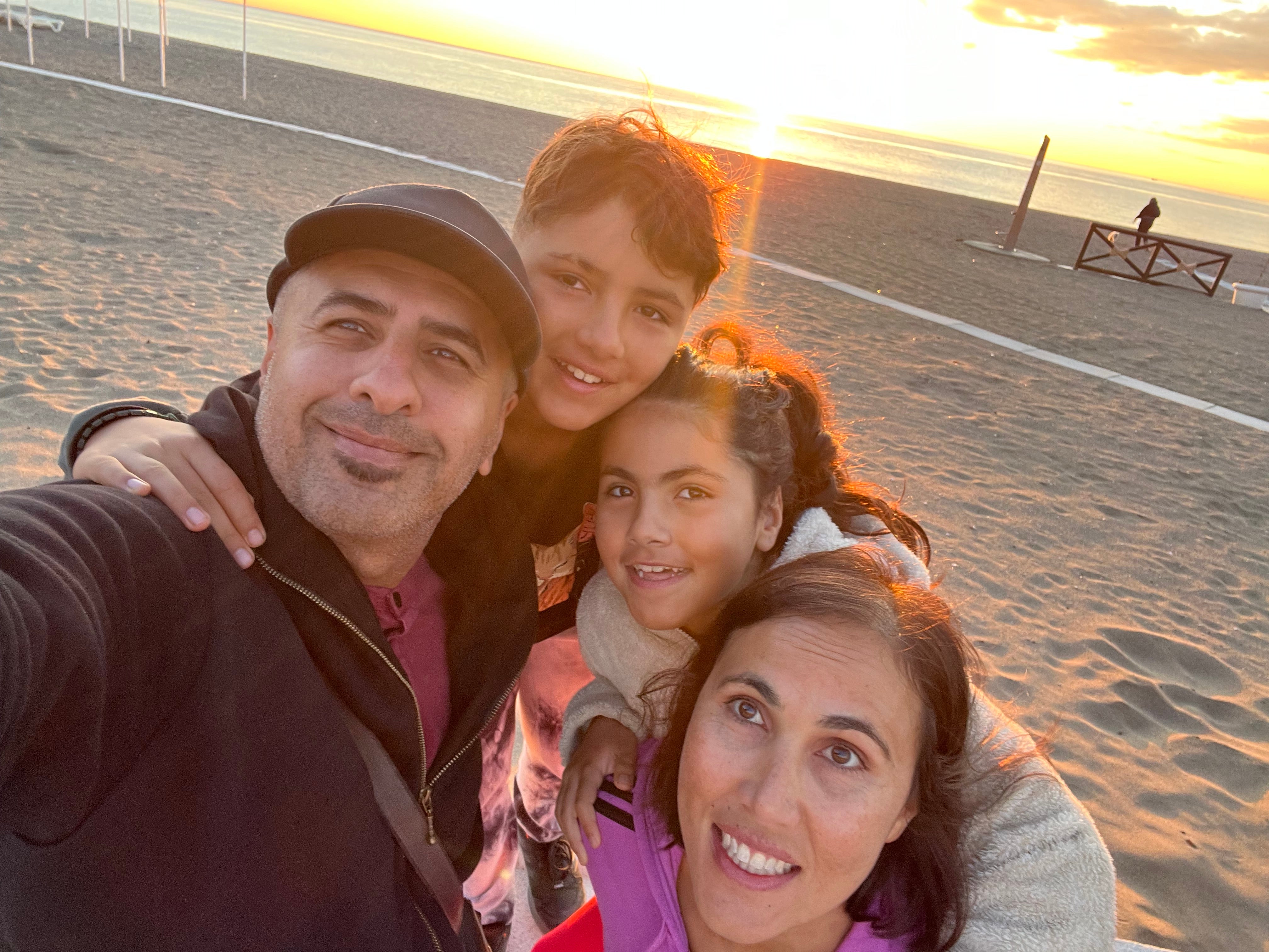 Woman and man with two children on a beach during sunset