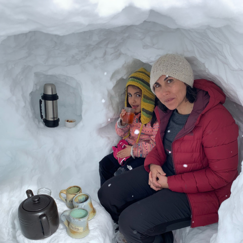 Woman and young girl sitting in snow cave