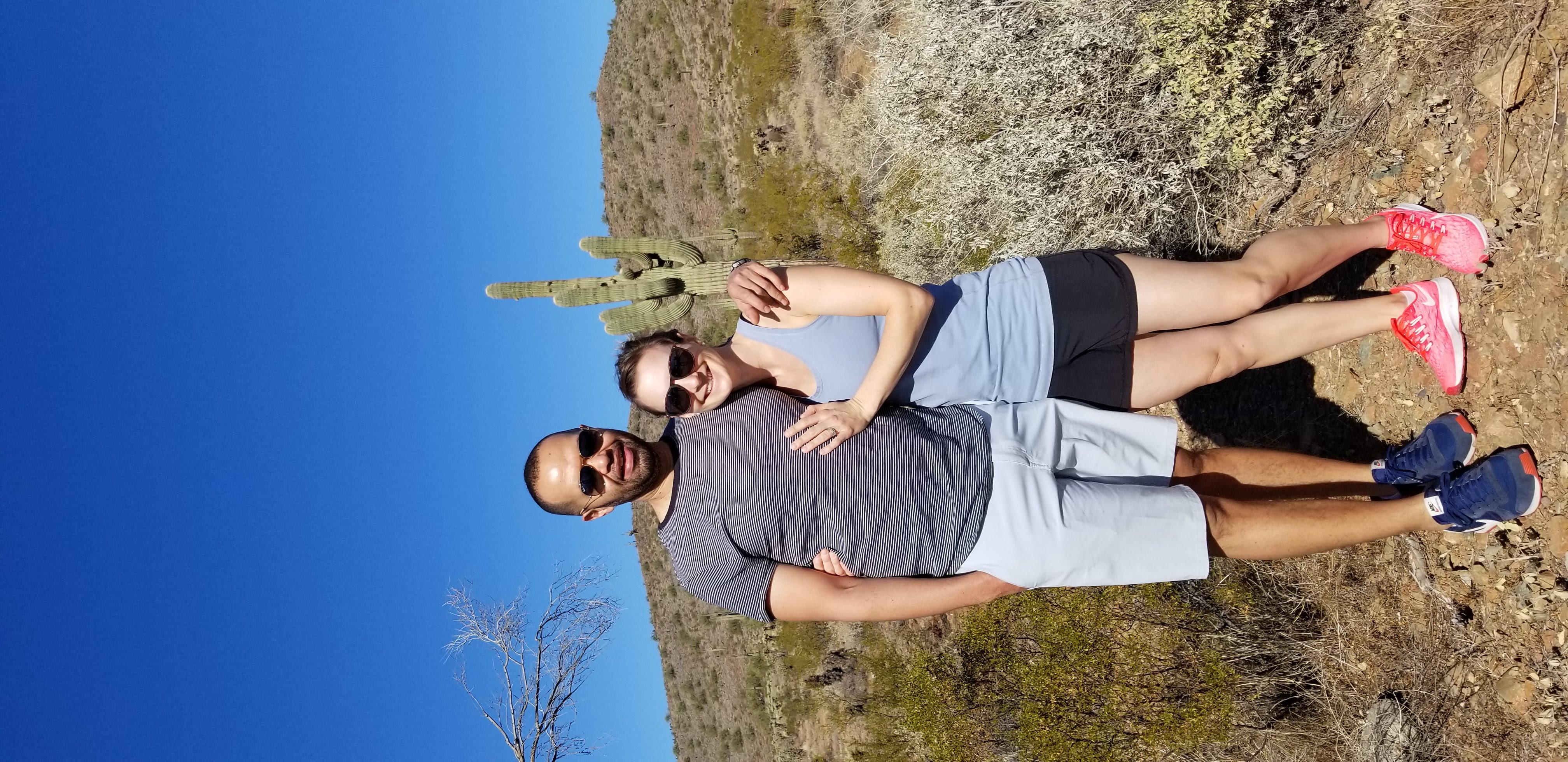 A man and woman standing in front of a hill.
