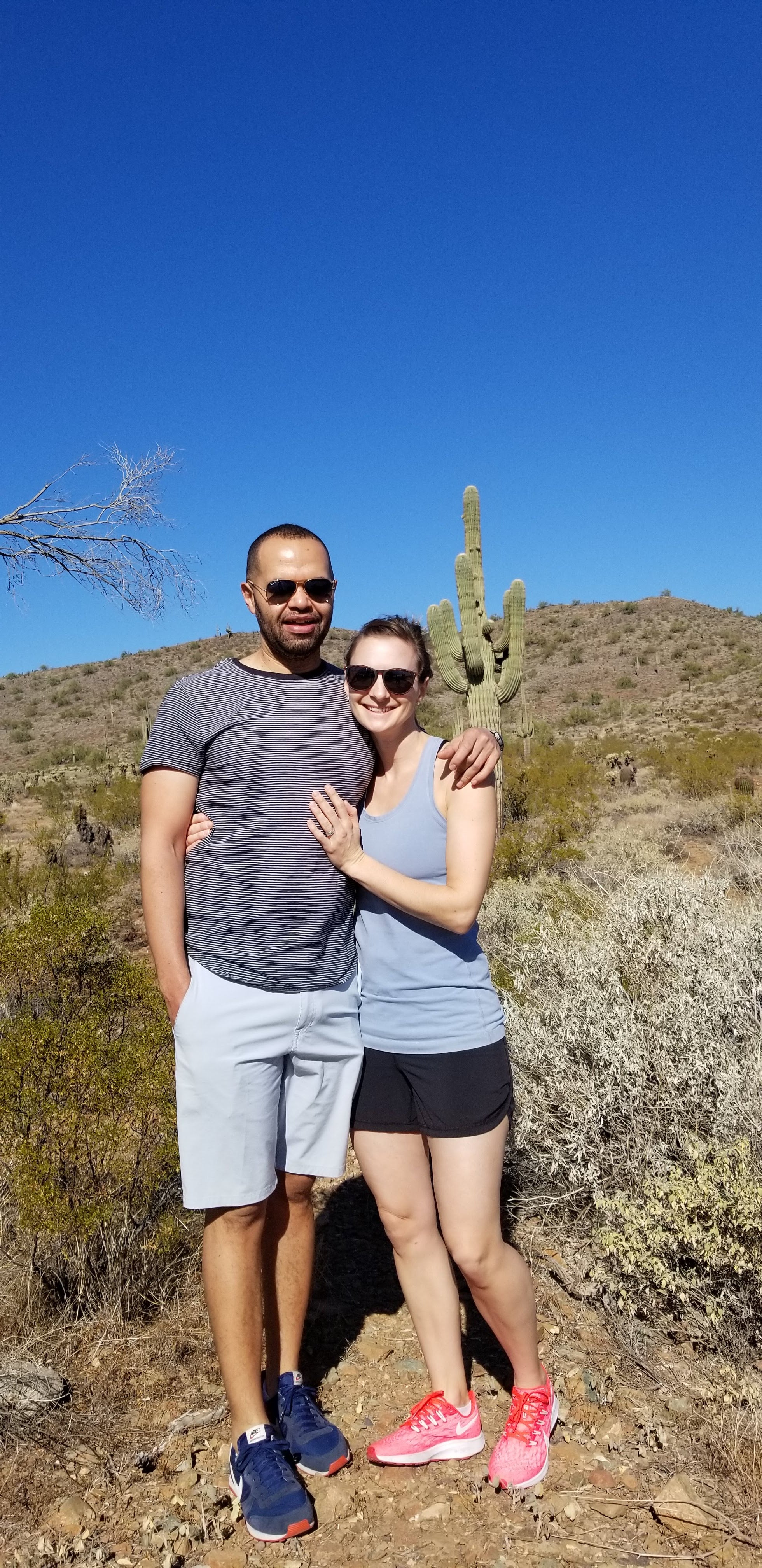 A man and woman standing in front of a hill.