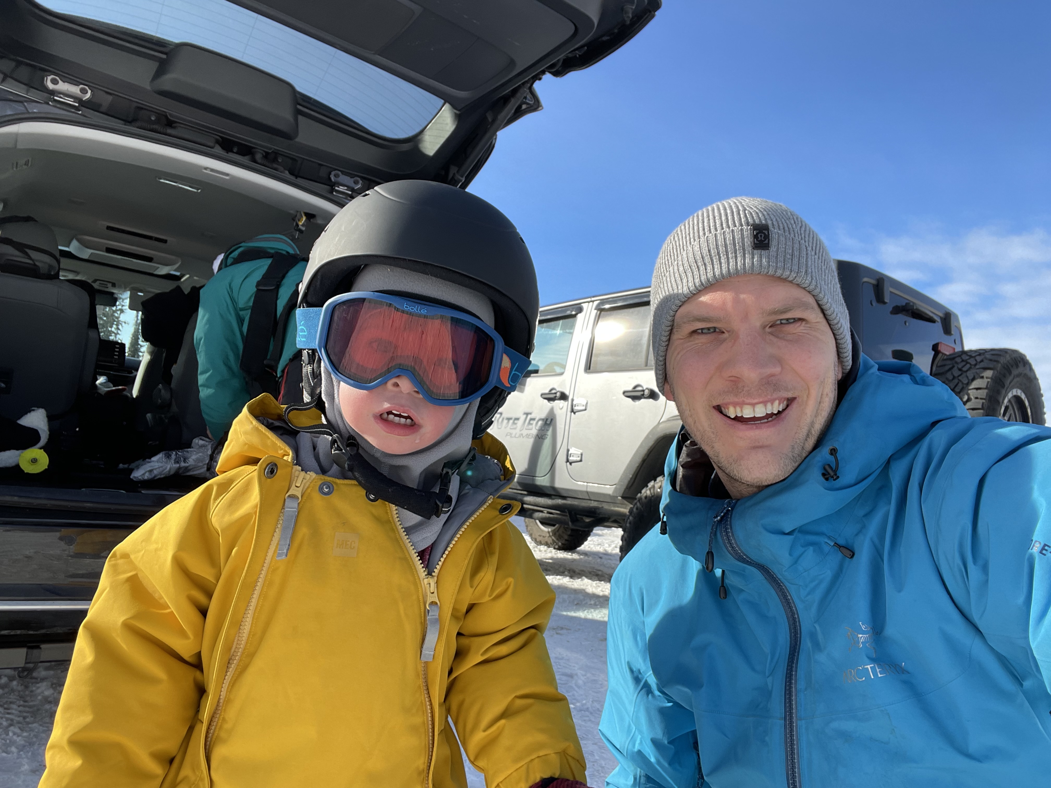 A man and a child with a ski helmet in winter jackets.